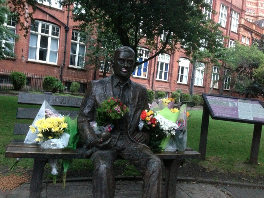 Alan Turing's Statue surrounded by flowers