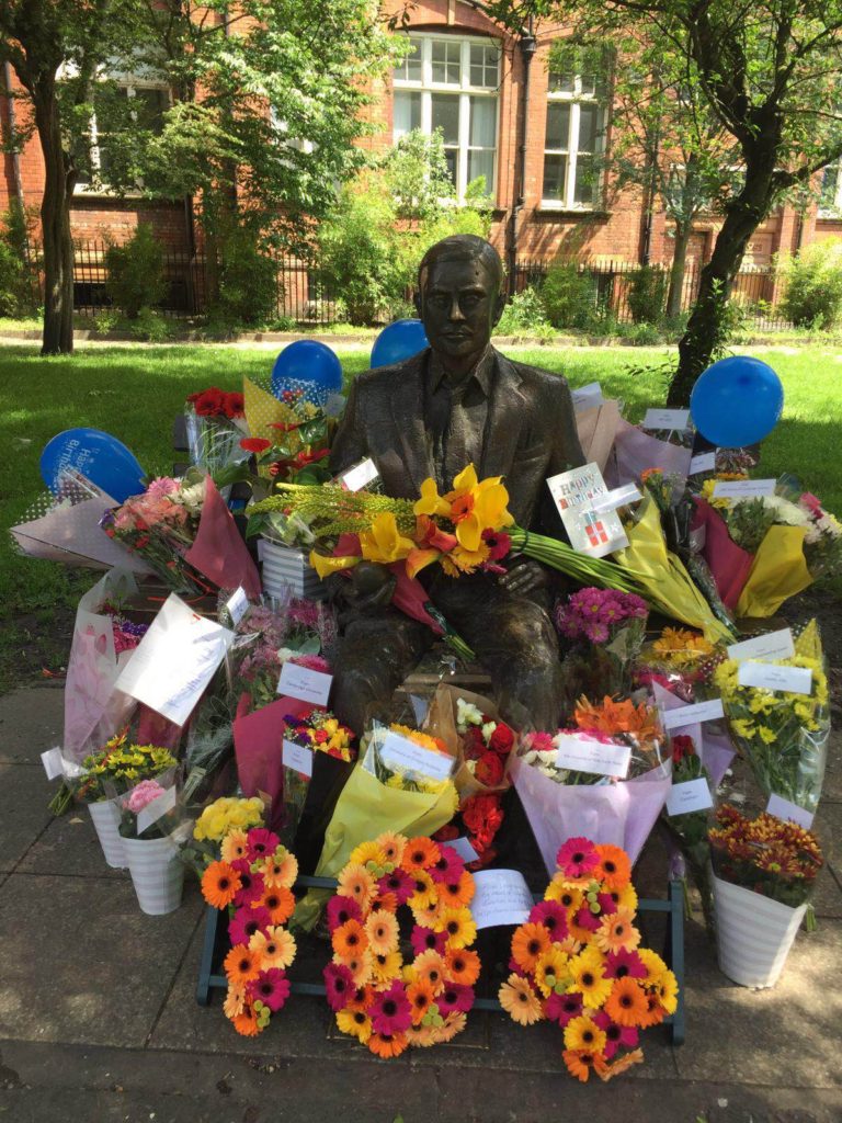 Alan Turing's Statue surrounded by flowers