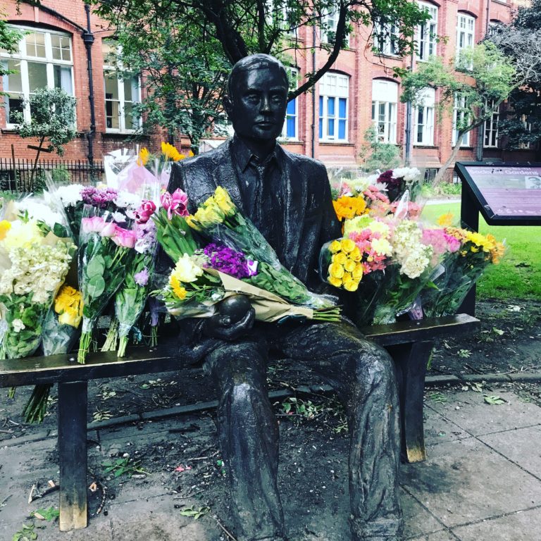 Alan Turing's Statue with lots of flowers